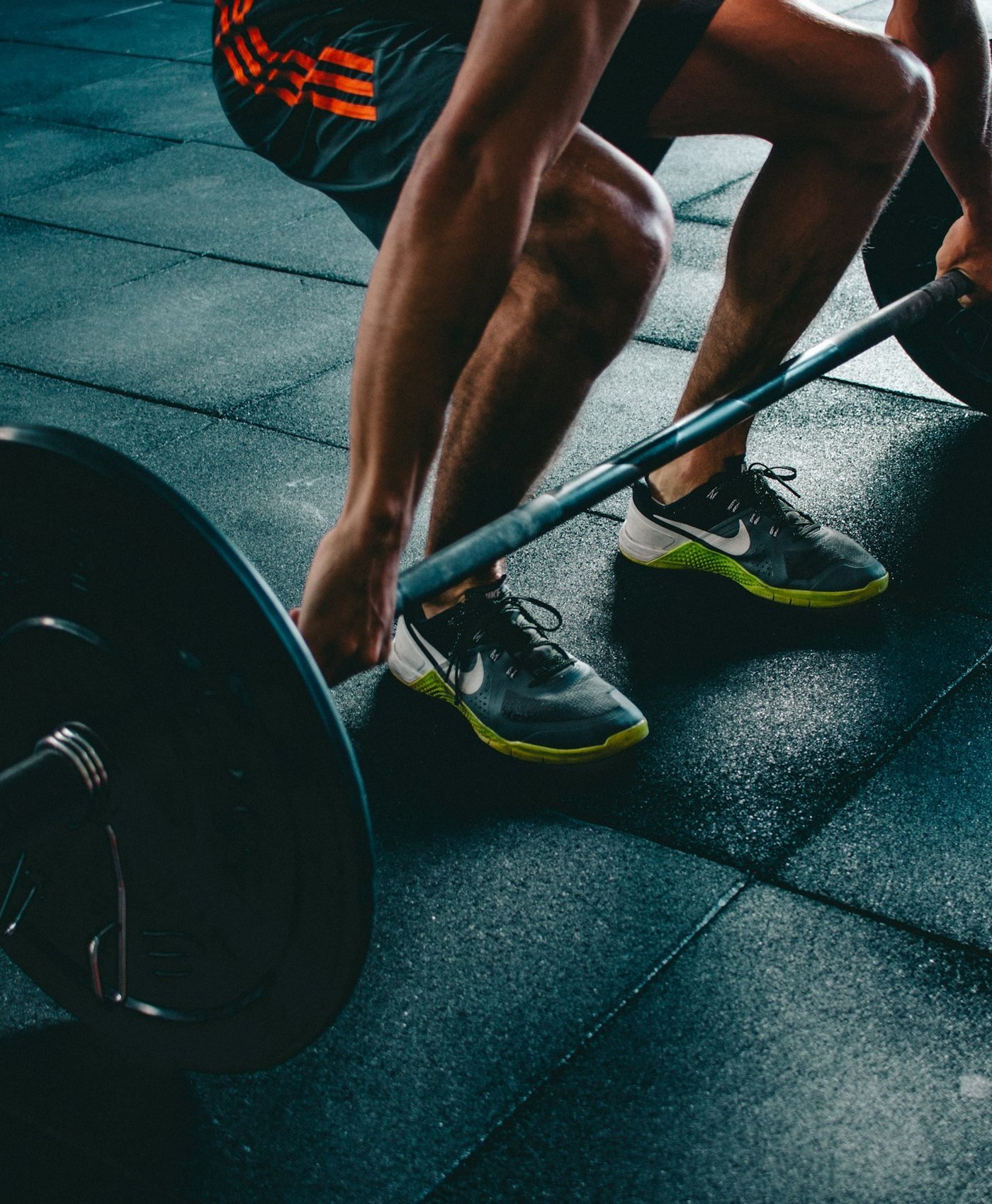 Lifter gripping a loaded barbell on a dark rubber gym floor